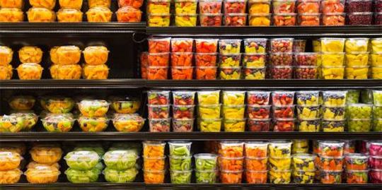 Assortment of cut fruit in plastic containers on display for sale at the supermarket