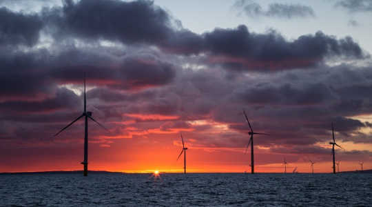 The sun rises behind an offshore wind farm. Image: Aaron via Flickr