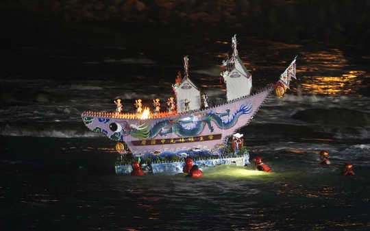 An elaborate model house is being guided into the ocean as an offering to wandering ghosts during the beginning of the Ghost Month Festival in Taiwan.