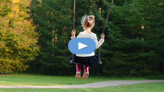 young girl, seen from the back, sitting on  a swing