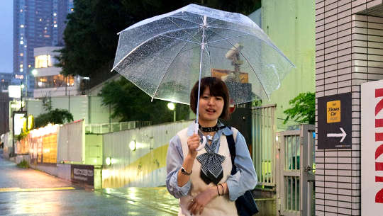 Smiling young girl walking with open umbrella