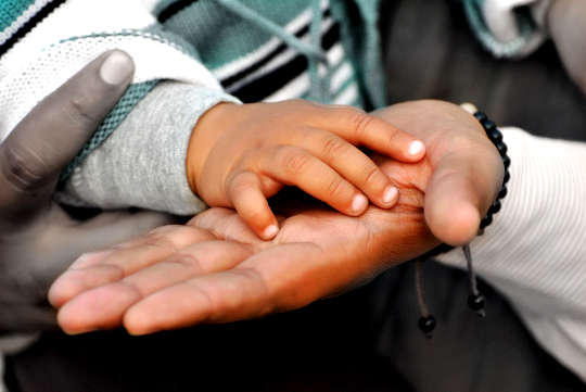 the hand of a baby resting in the open palm of an adult