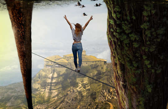 a woman standing on a high-wire with her arms raised up in victory