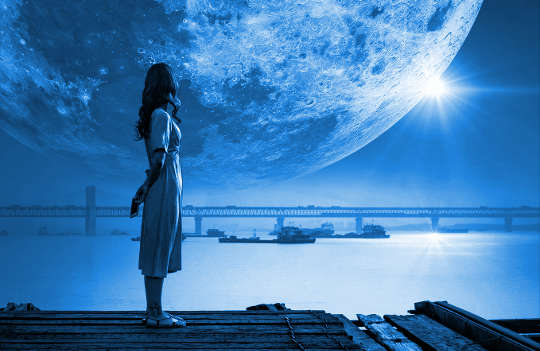 a woman standing with a huge moon in the background