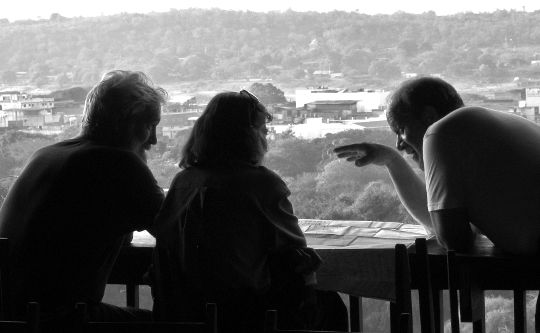 three people sitting at a table in deep conversation