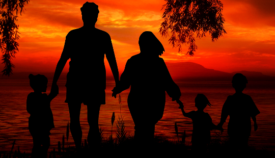 a family holding hands and standing ankle deep in water