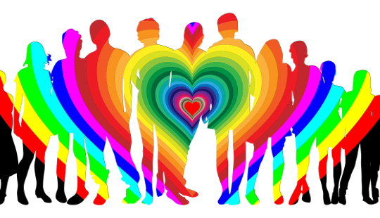 a group of people standing in a rainbowed heart