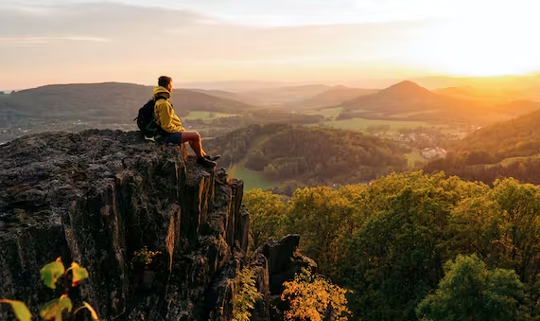 a hiker sitting on an outcrop of rocks out in nature