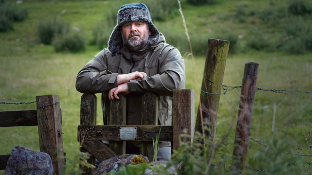 pensive man leaning on a gate