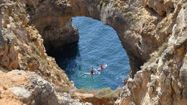 two kayaks on the water passing under a stone arch