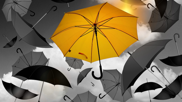 a bright yellow umbralla amidst black umbrellas