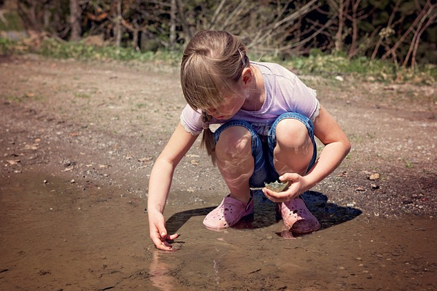 a young girl squatting down and playing with the earth