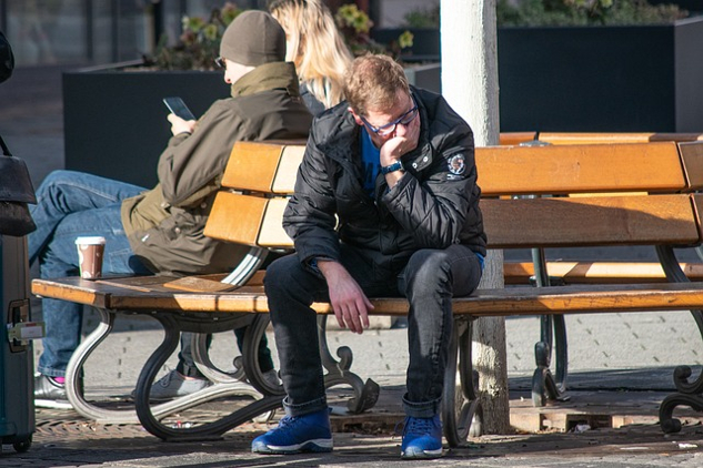 a man sitting on a bench with his face in his hands