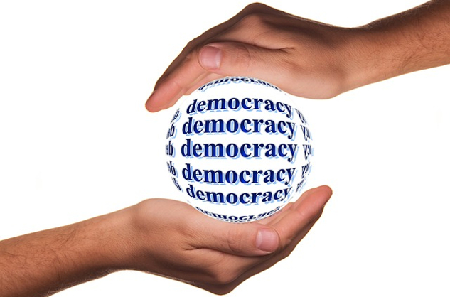 two hands protectively holding a globe named Democracy