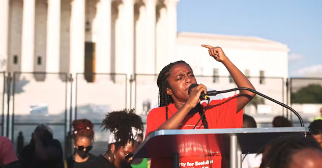 Racialized woman speaking at a protest, highlighting the challenges and backlash faced while advocating for social change.