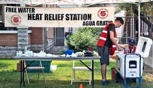 Workers stock water at a heat relief station offering free water