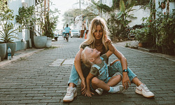 mother and child sitting on the ground in the middle of a cobblestone street