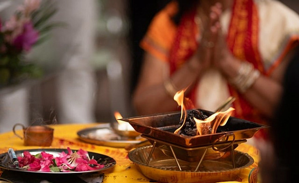 a person in meditation in front of a bowl of flower petals and a bowl of fire