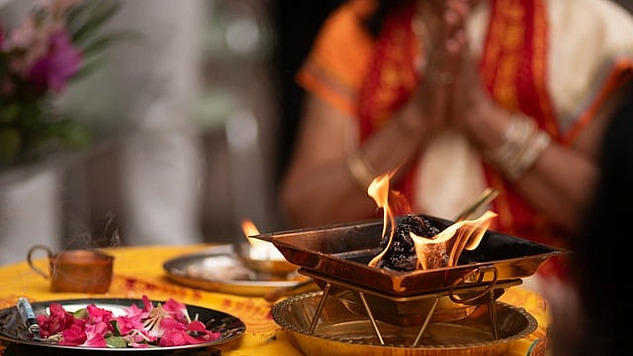 a person in meditation in front of a bowl of flower petals and a bowl of fire