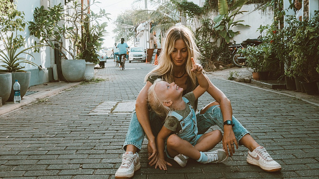 mother and child sitting on the ground in the middle of a cobblestone street