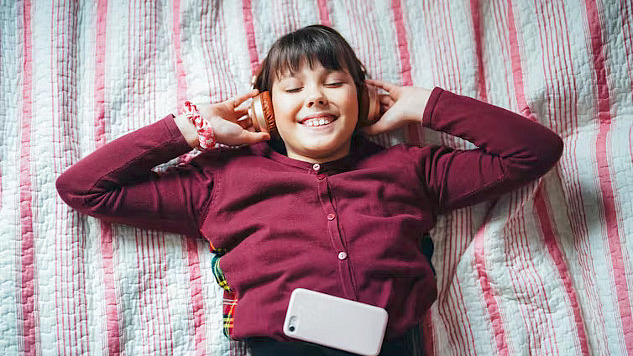 Child listening to an audiobook with headphones, illustrating enhanced imagination and intellectual development.