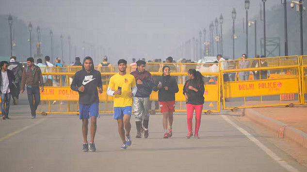 Men running through smog in Delhi, highlighting the impact of air pollution on athletes' health and performance.