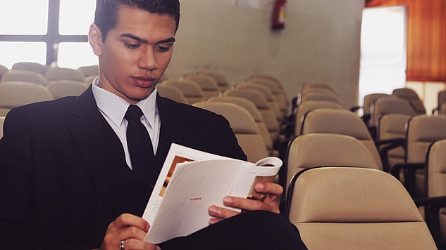 a young man sitting reading in an empty lecture hall