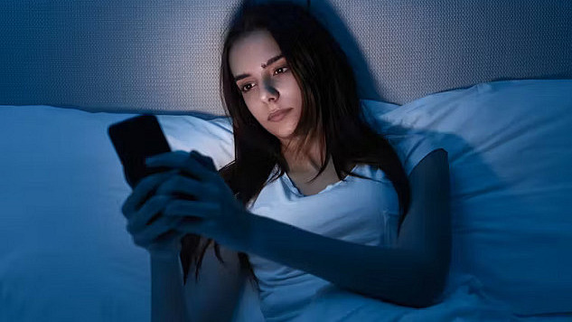 Close-up of a person using a smartphone at night, highlighting concerns about blue light exposure and its potential effects on skin health