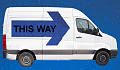 a white van with a huge sign on its side: This Way