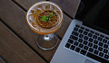 open laptop with a cocktail next to it