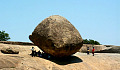 people sitting in the shade of a huge rock