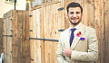 young white man wearing  a suit standing in from of closed doors