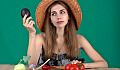 a woman with an array of fresh vegetables in front of her and holding up an avocado