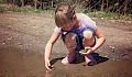 a young girl squatting down and playing with the earth