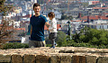 a young child walking on top of a stone wall with father standing by smiling and holding the child's hand