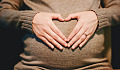 woman's hands forming a heart shape on top of her womb