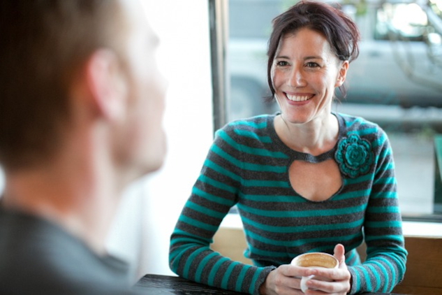 a smiling woman having a cup of coffee with someone