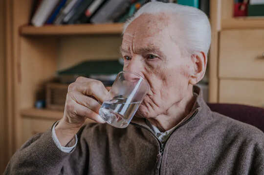 man drinking clear liquid from a cup