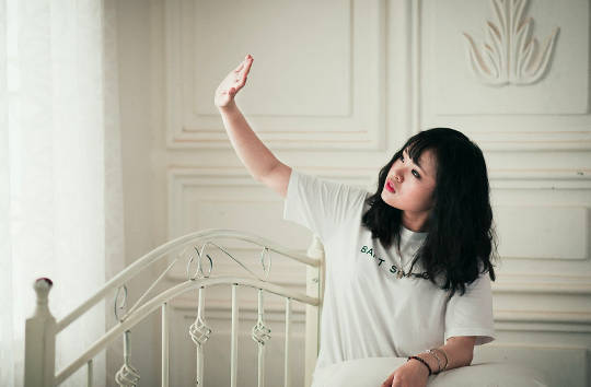 young woman sitting on her bed