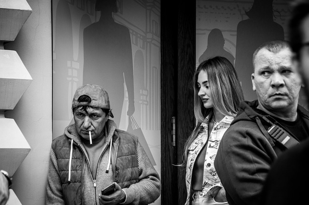 a man lighting a cigarette, with two other people looking at him