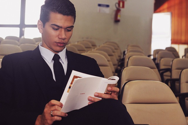 a young man sitting reading in an empty lecture hall