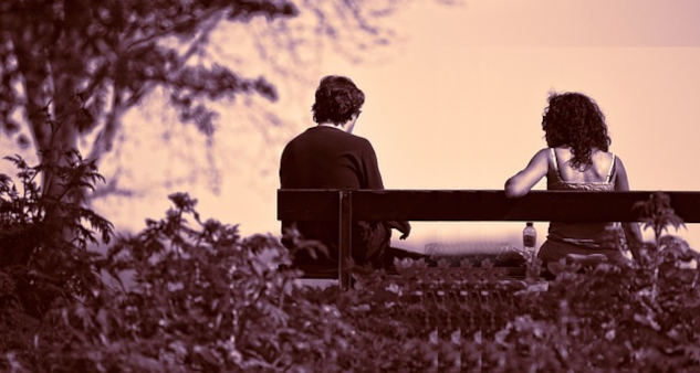 two people sitting far apart on a bench