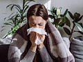 A person sitting indoors with natural light, surrounded by plants, emphasizing the positive impact of the indoor microbiome on health.