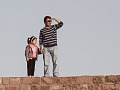 a father and daughter standing on a stone wall with the father looking into the distance