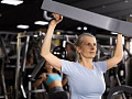 Woman uses weights at the gym to build strength and prevent muscle loss.