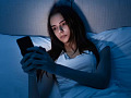 Close-up of a person using a smartphone at night, highlighting concerns about blue light exposure and its potential effects on skin health