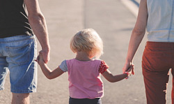 a child holding hands with her parents - one on each side