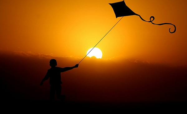 a child flying a kite under the bright shining sun