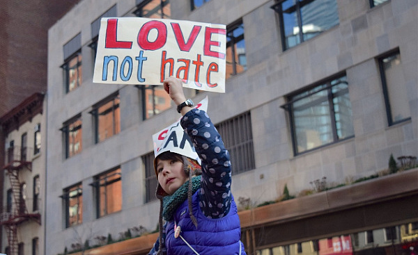 a young woman holding up a sign that reads: Love not Hate