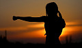 young woman practicing karate outside at sunset